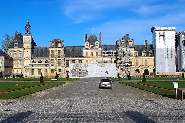 The Cour du Cheval Blanc at Fontainebleau: the wide gravel courtyard with the brick-and-stone wings of the château on a sunny day.