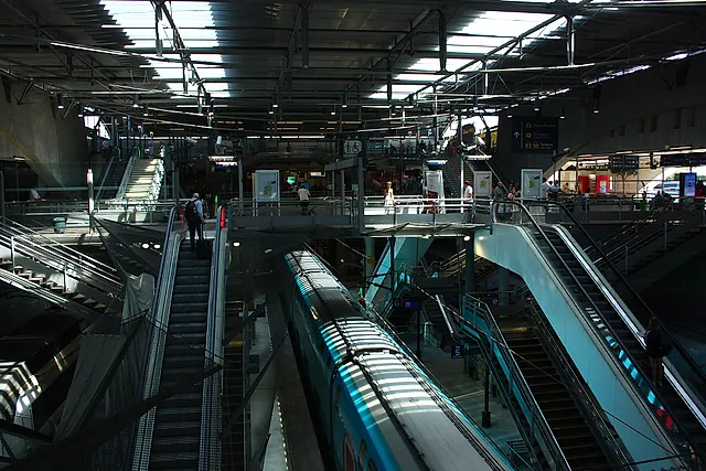 The platforms of Marne-la-Vallée–Chessy station seen from above, with escalators and trains waiting below the station roof.