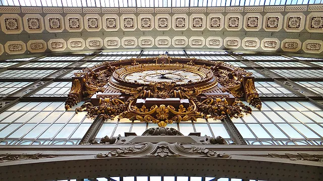 One of the great glass clocks of the Musée d'Orsay, set in an ornate gilded frame against the glass roof of the former station.