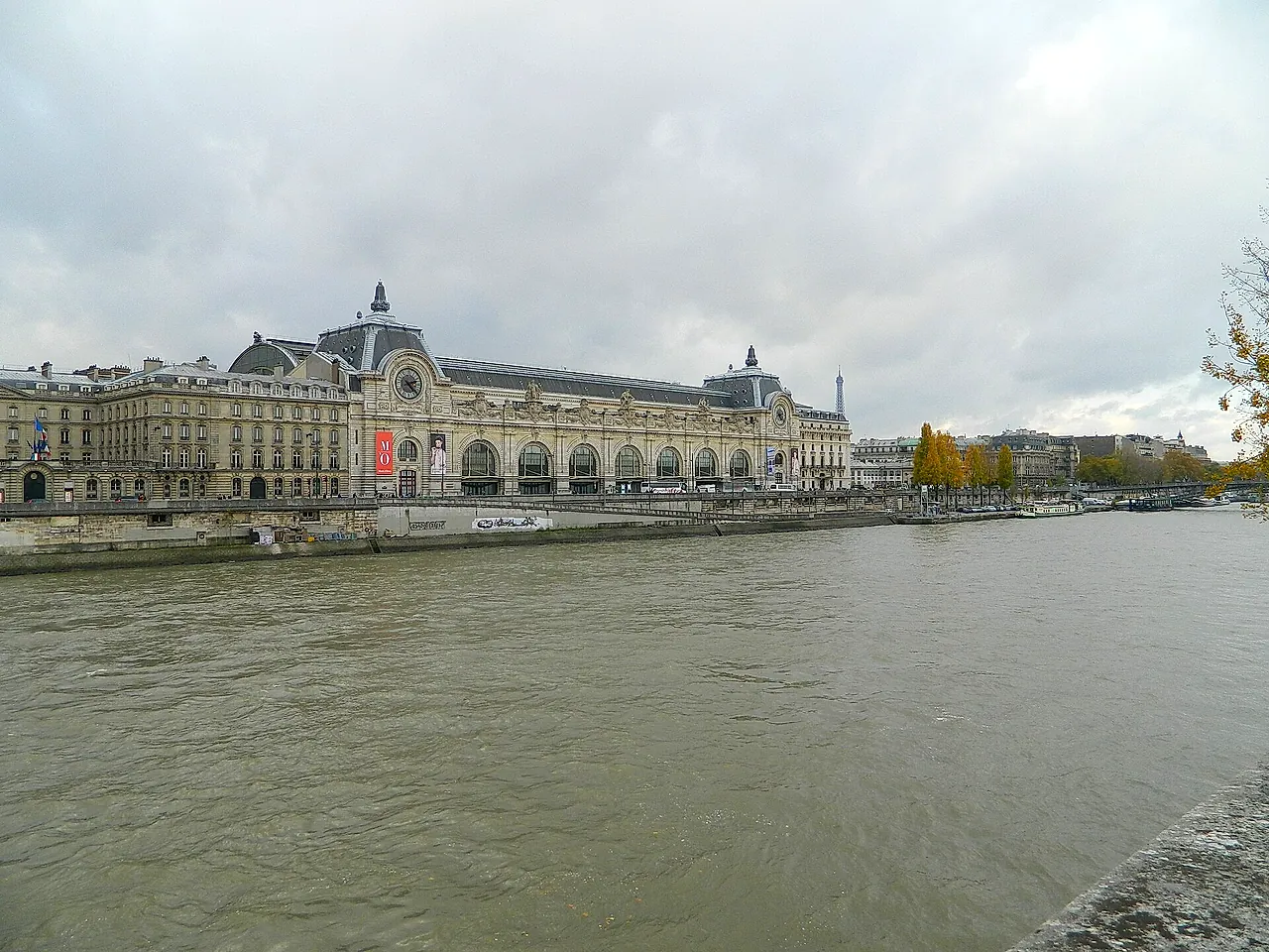 The stone facade of the Musée d'Orsay seen from the river bank, with its long arched front along the Seine.