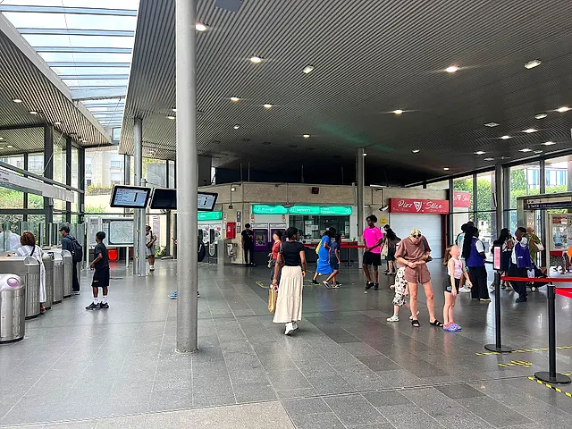 The ticket hall of Val d'Europe station with fare gates, information screens and a few travellers.